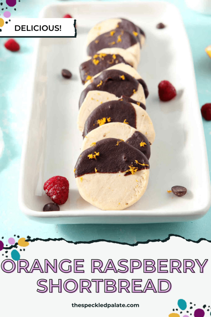 A tray of cookies lined up that are partially dipped in chocolate with the text Orange Raspberry Shortbread Cookies