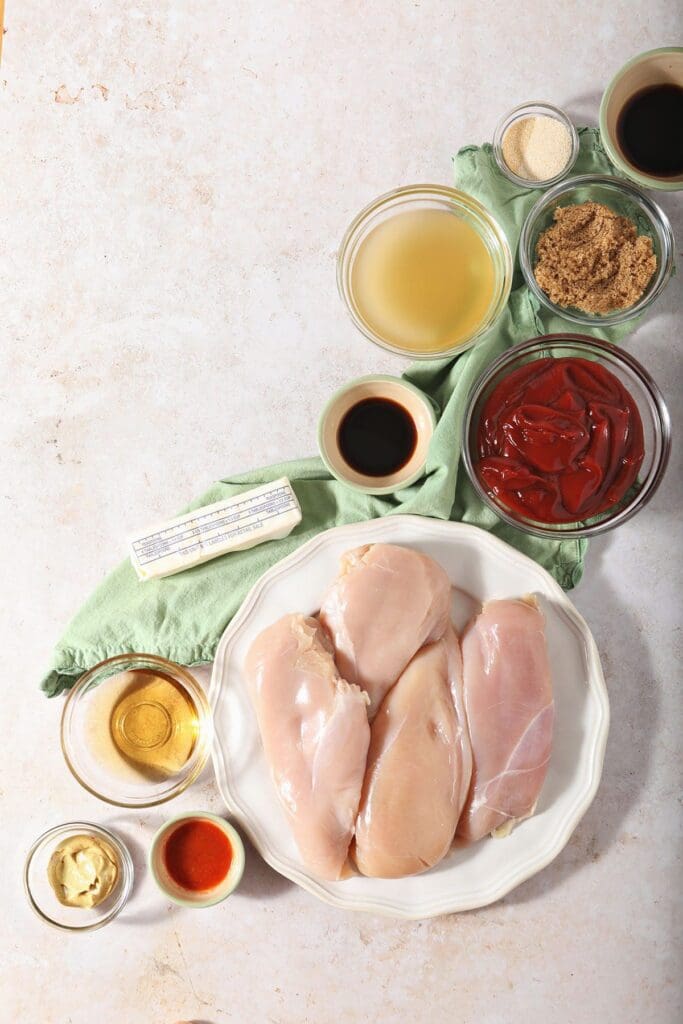 Raw chicken with other ingredients in bowls on a countertop