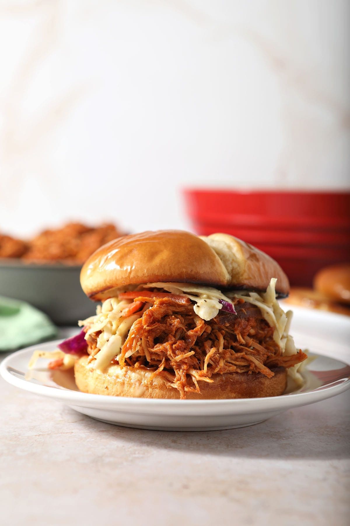 A BBQ chicken sandwich with slaw on a white plate