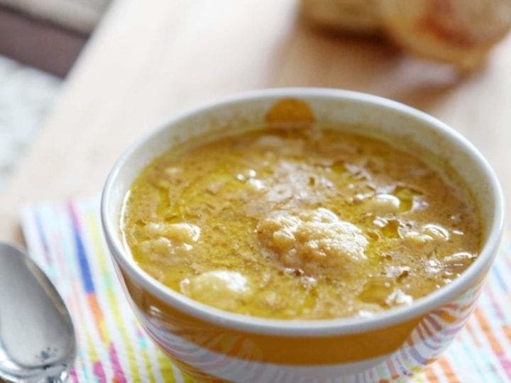 Bowl of roasted cauliflower cheddar soup with spoon on napkin