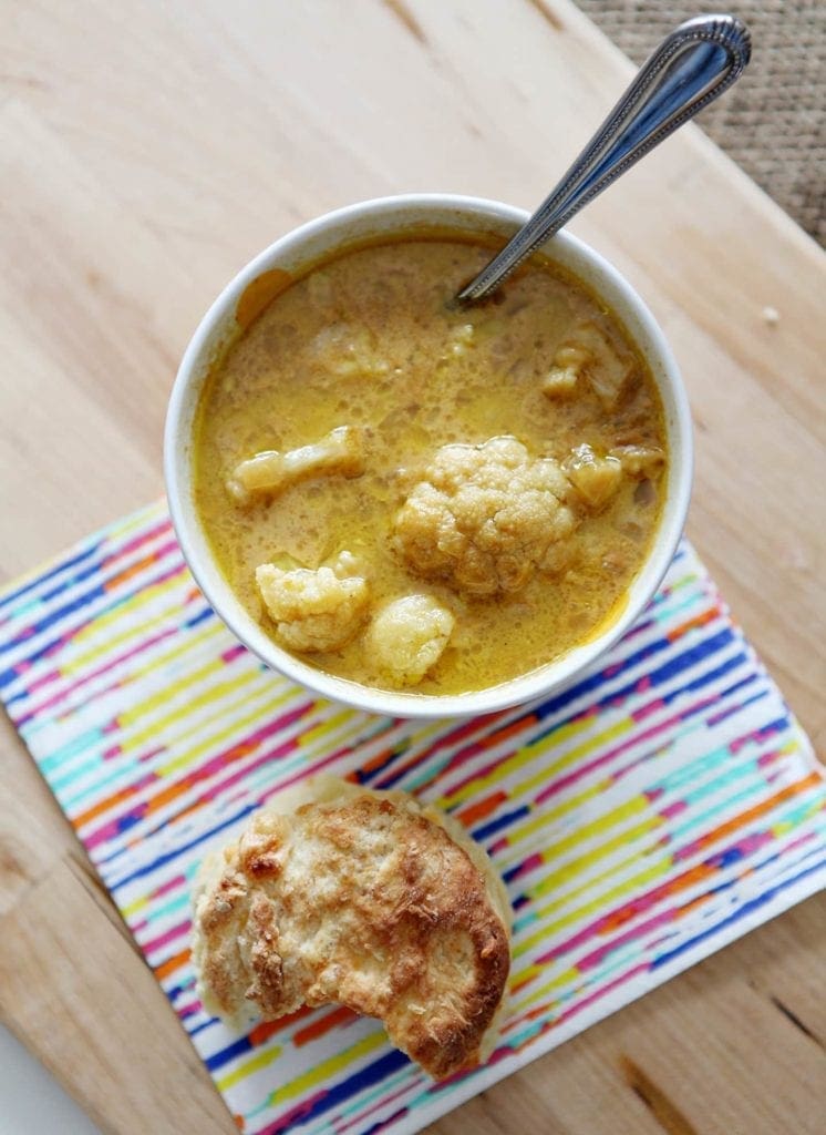 Overhead view of roasted cauliflower cheddar soup with spoon on napkin 