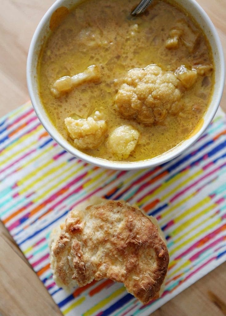 Overhead view of bowl of soup next to bread with a bite taken out 