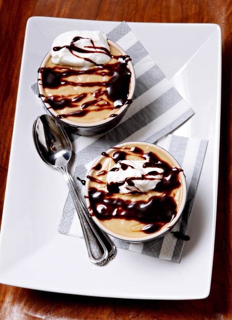 Two bowls of butterscotch pudding with chocolate drizzle 