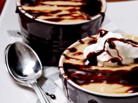 Close up of two butterscotch pudding bowls next to spoons 