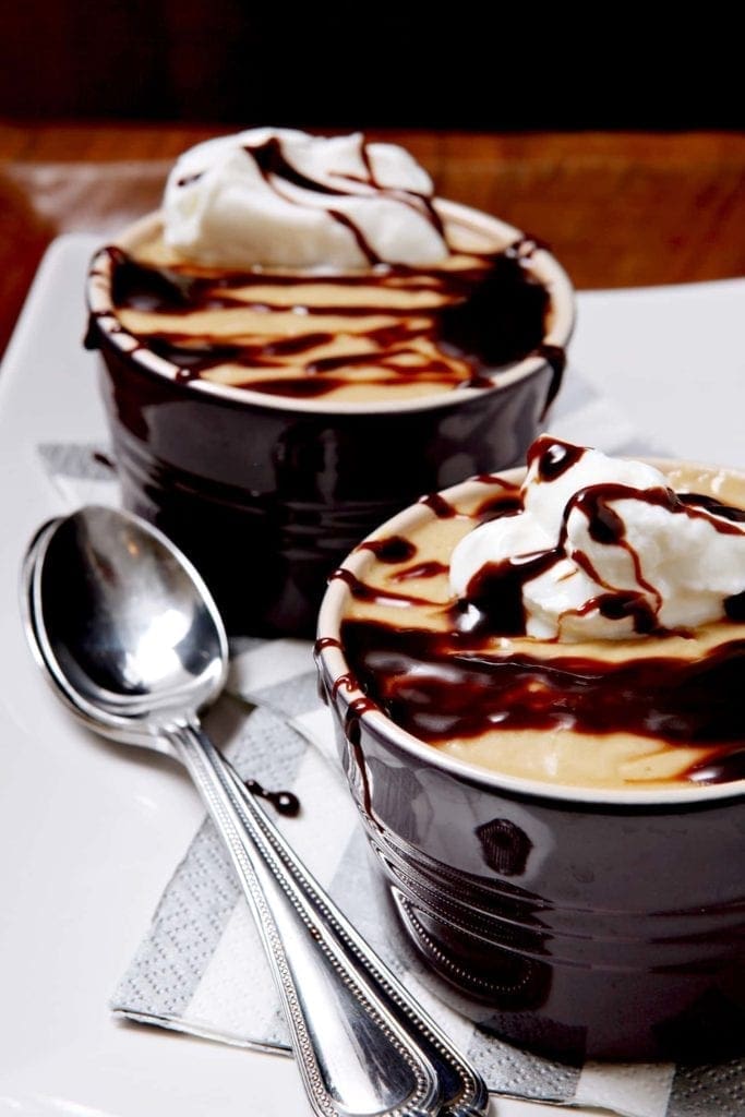 Close up of two butterscotch pudding bowls next to spoons 