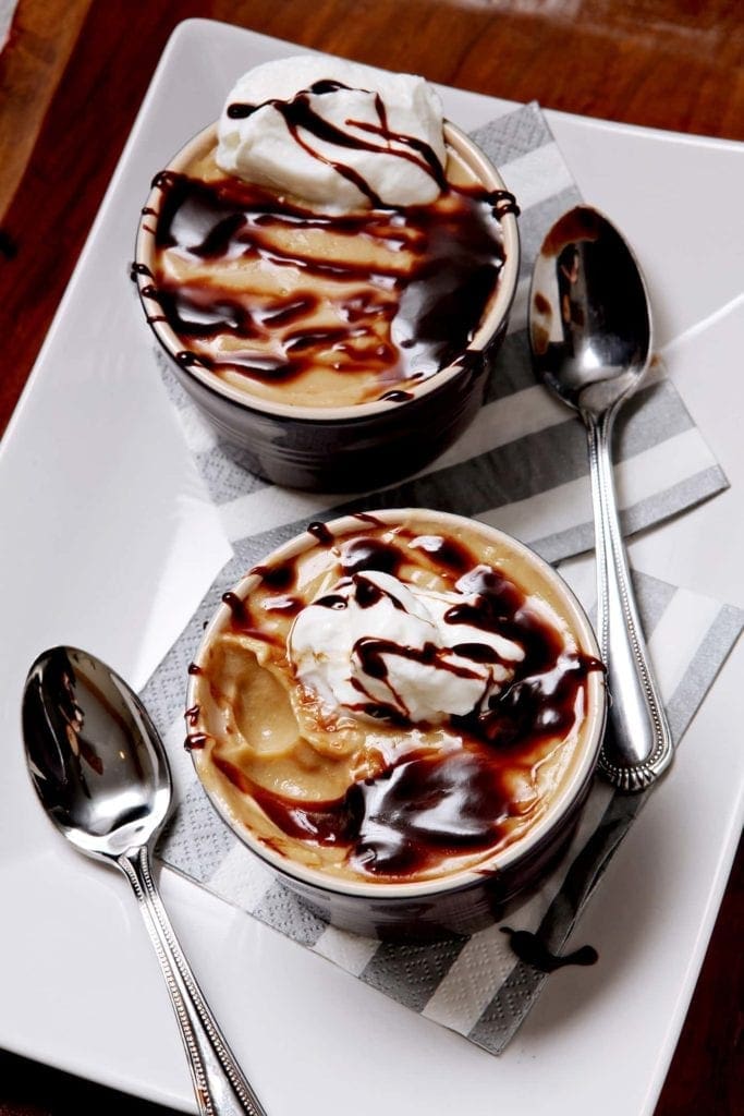 Overhead view of pudding bowls on napkins next to spoons 