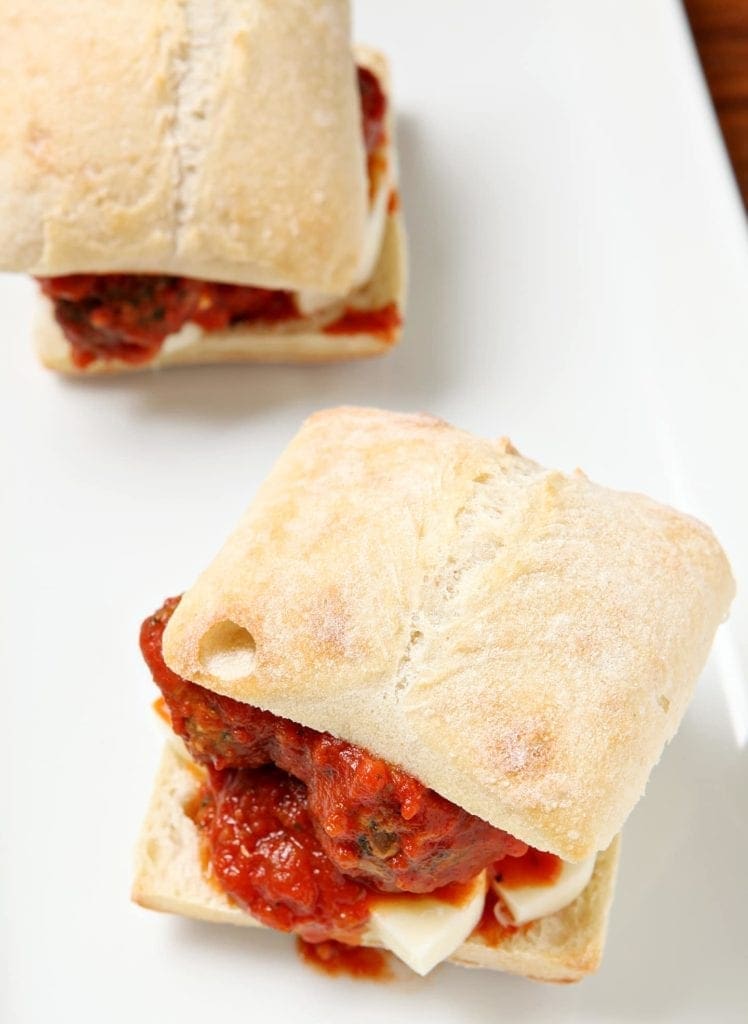 Overhead view of cut meatball sub on white plate 