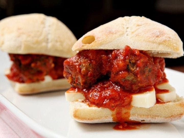 Close up of turkey spinach meatball subs on white plate 
