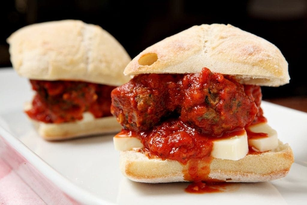 Close up of turkey spinach meatball subs on white plate 