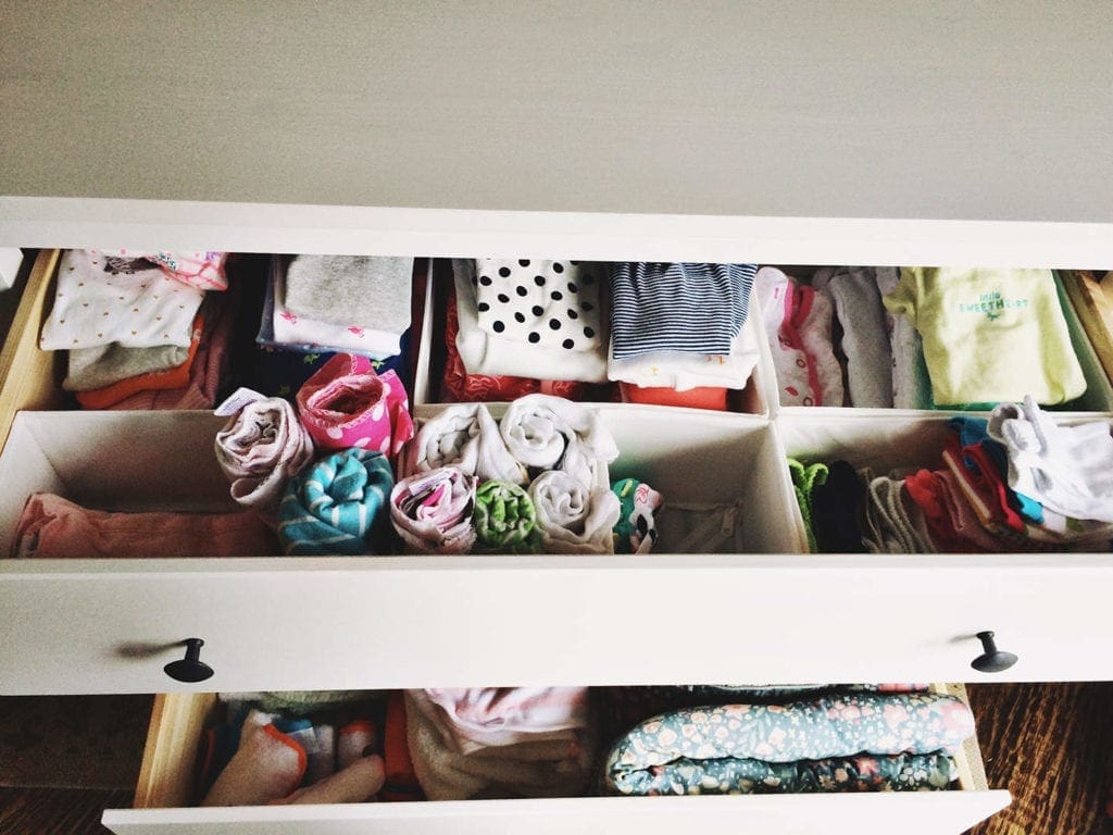 An opened drawer with organized baby clothes 