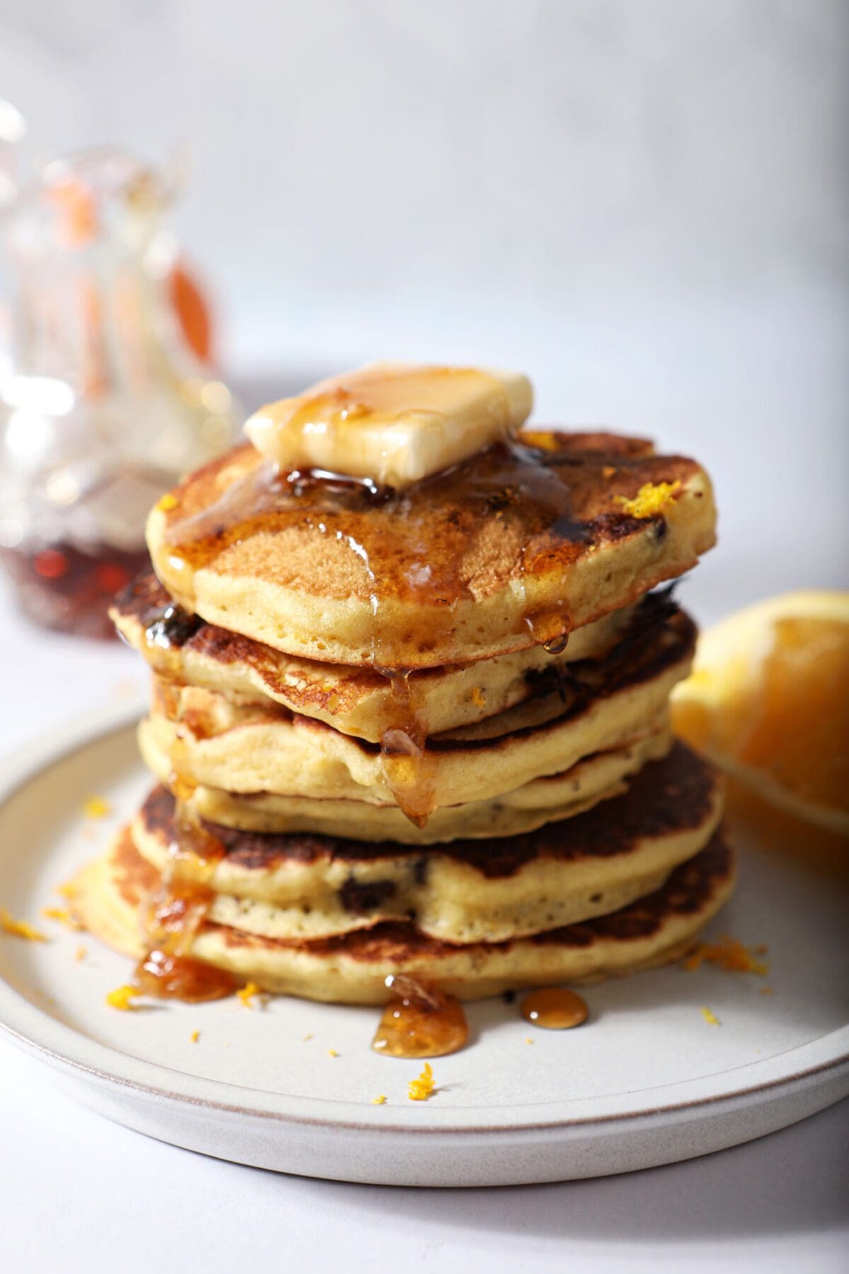 A stack of orange pancakes topped with butter and syrup