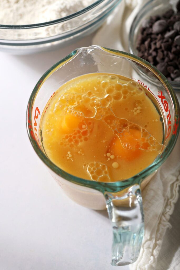 Wet ingredients for orange pancakes in a liquid measuring cup