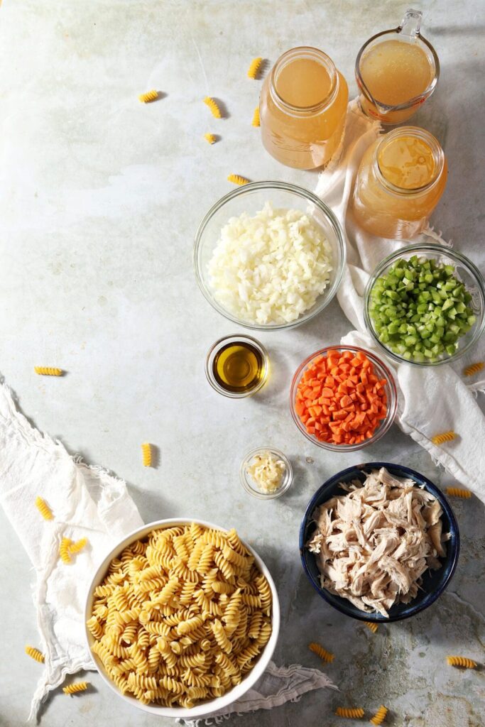 Ingredients to make a comforting soup in jars and bowls on a green countertop