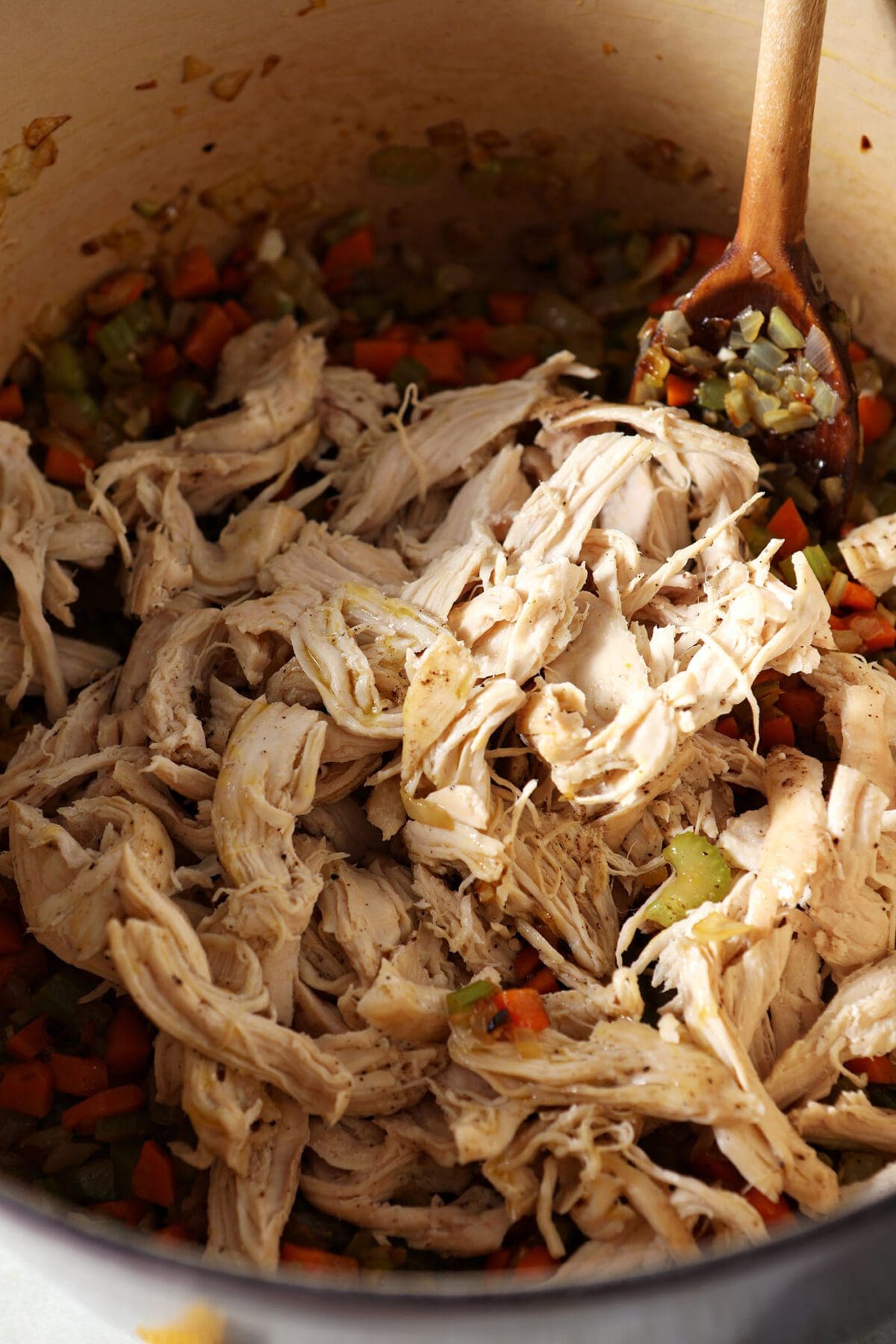 Shredded rotisserie chicken in a pot with mirepoix