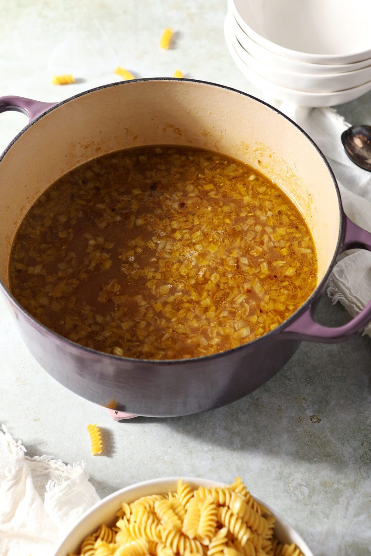 A Dutch oven of chicken noodle soup before the noodles are added