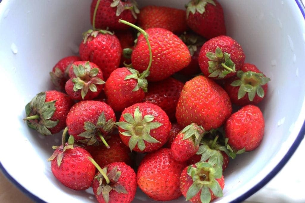 A white bowl filled with strawberries 