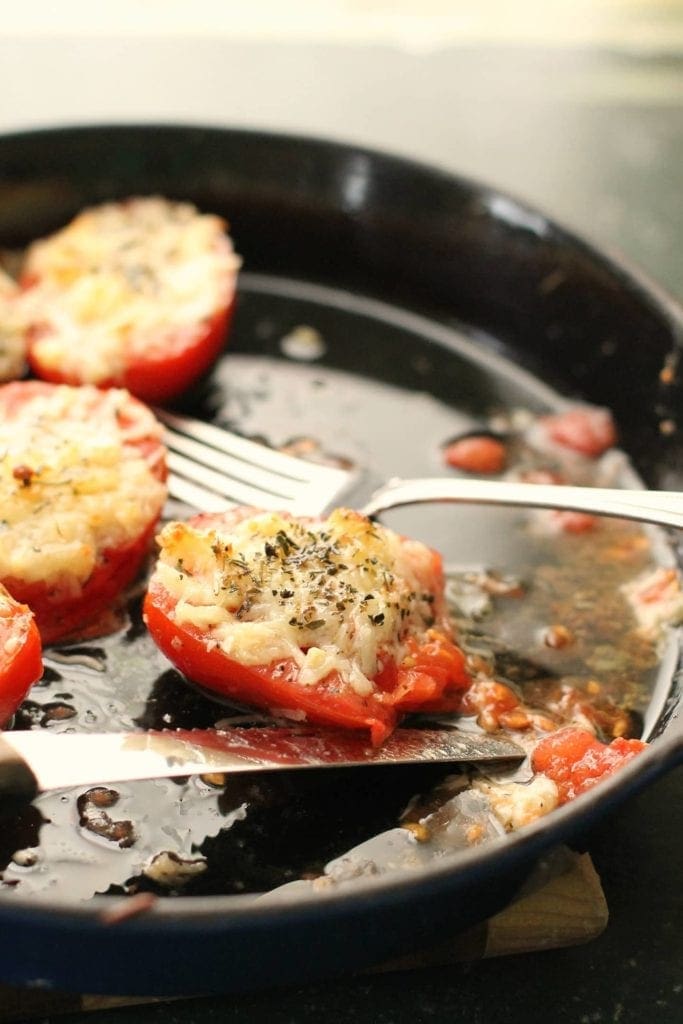 Dish of roasted tomatoes with fork and knife 