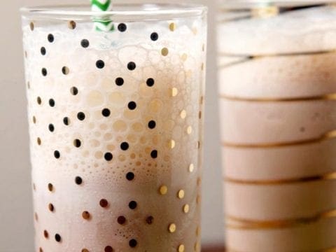 Close up of two glasses holding milkshakes with green straws