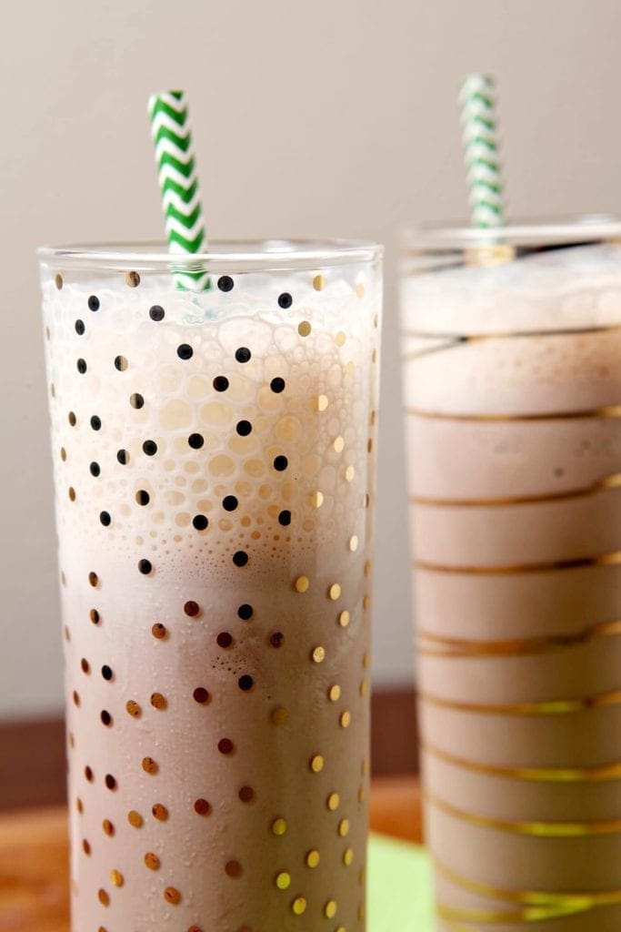 Close up of two glasses holding milkshakes with green straws