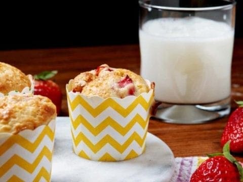 Muffins in yellow and white containers next to glass of milk