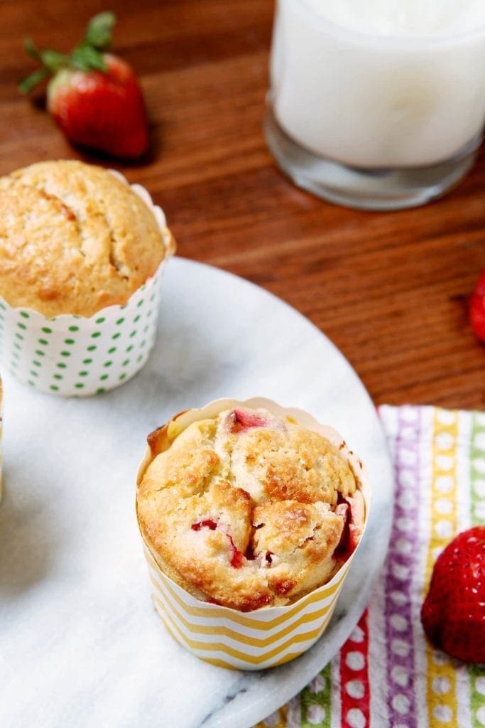 Overhead angled view of muffins on display table next to glass of milk