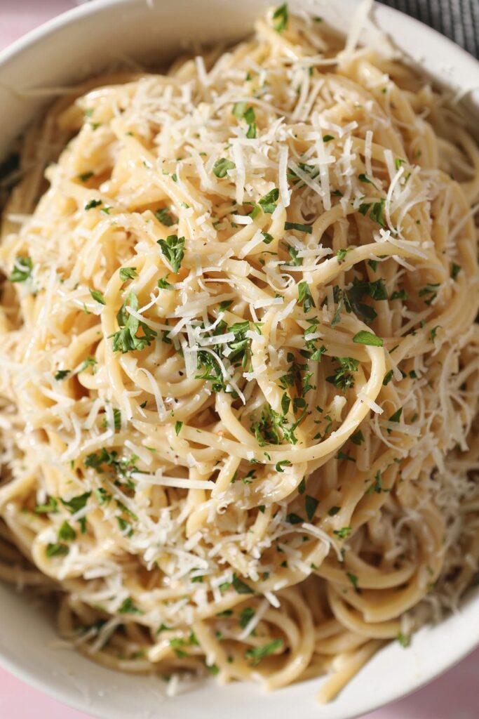 A bowl of authentic cacio e pepe garnished with cheese and parsley