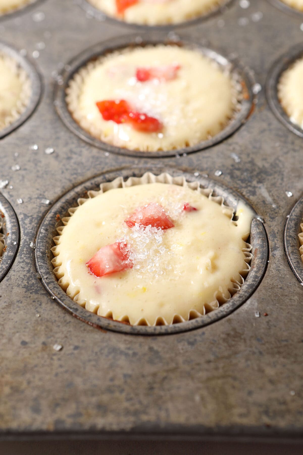 muffin batter in a muffin tin sprinkled with raw sugar before baking