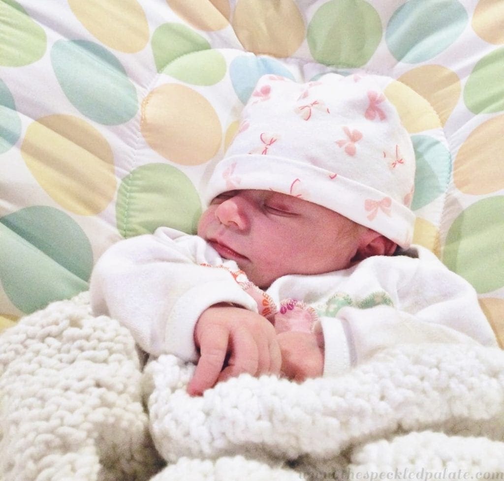 A newborn baby sleeping in a bassinet 