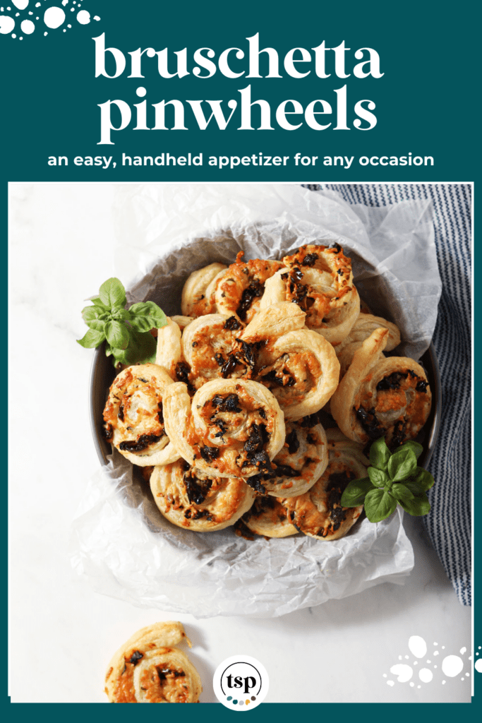 Overhead image of puff pastry pinwheels in a bowl surrounded by fresh basil and a blue linen with the text bruschetta pinwheels an easy, handheld appetizer for any occasion