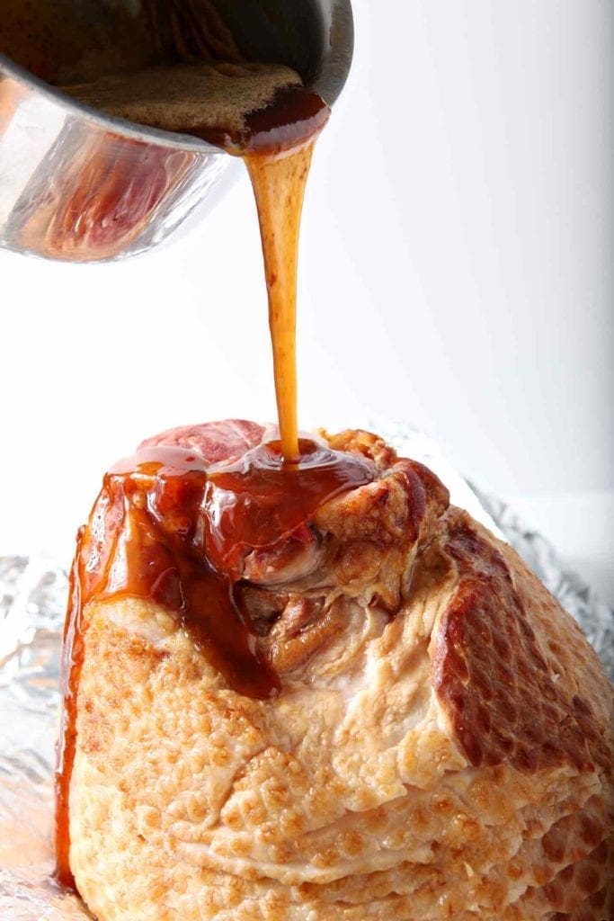 Honey glaze pours onto a smoked ham before baking