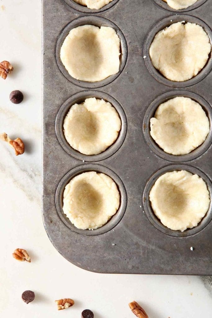 The crust of the Mini Bourbon Chocolate Pecan Pies is prepared before filling.