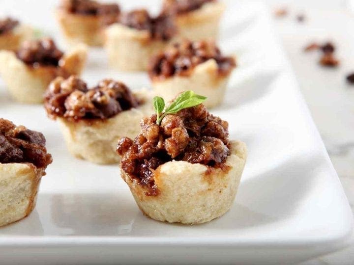 Mini Bourbon Chocolate Pecan Pies, after baking, on a white platter.
