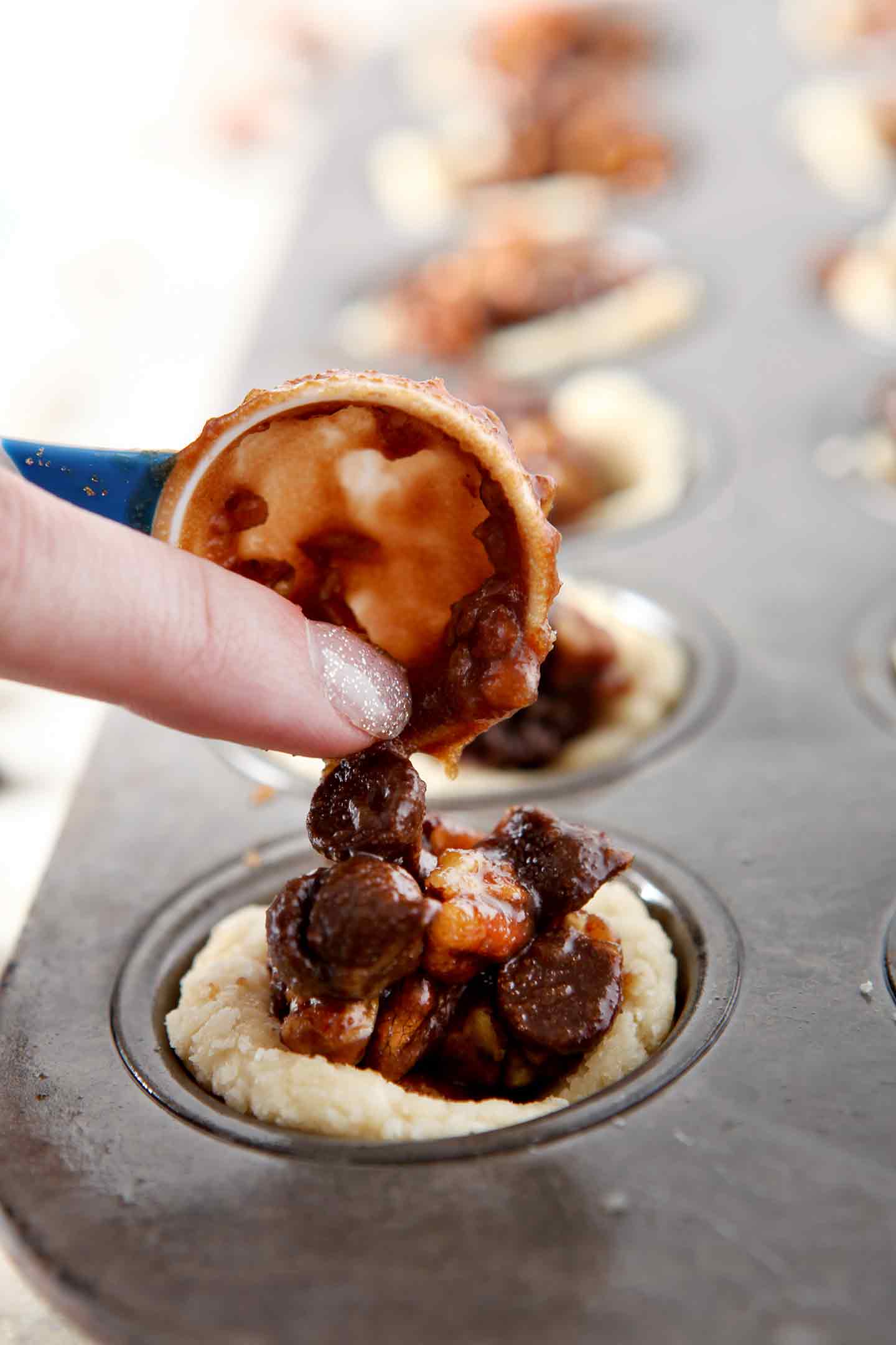 The filling is dolloped into the shells of the Mini Bourbon Chocolate Pecan Pies before baking