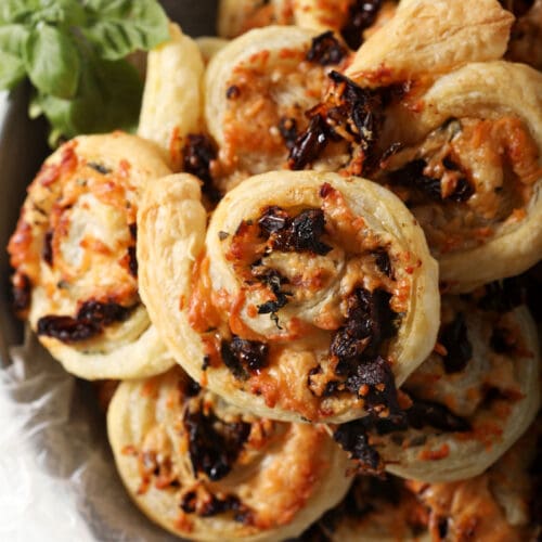 Close up of bruschetta pinwheels in a bowl with fresh basil