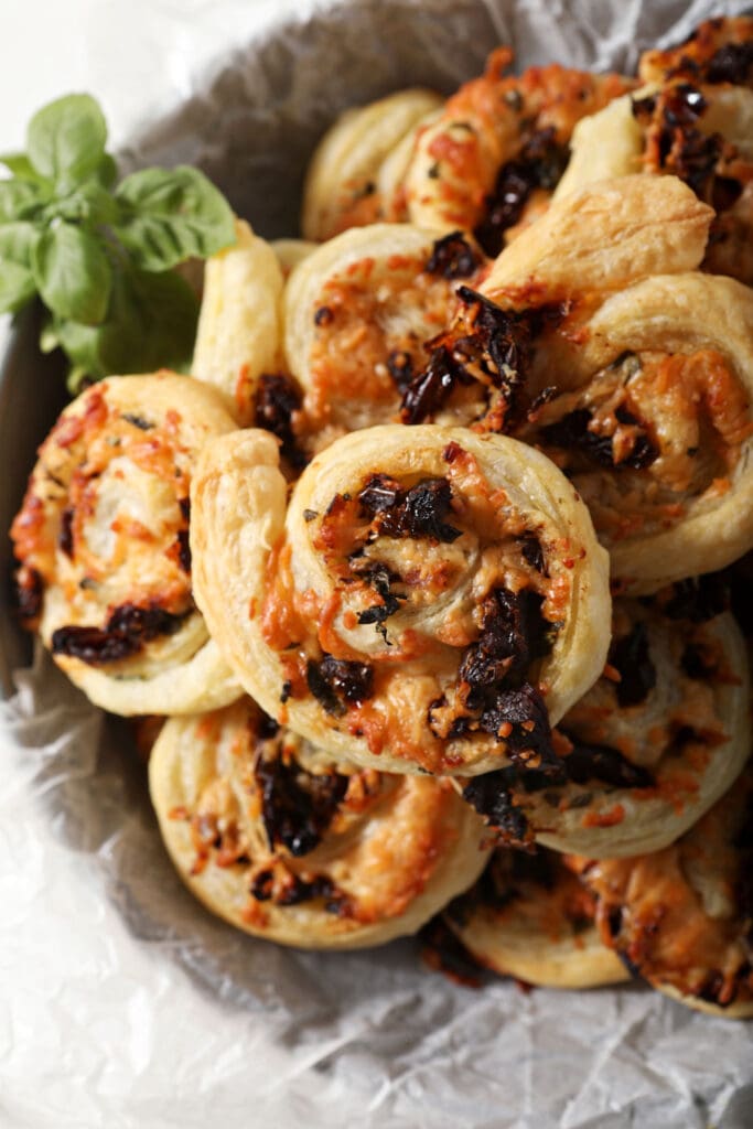 Close up of bruschetta pinwheels in a bowl with fresh basil