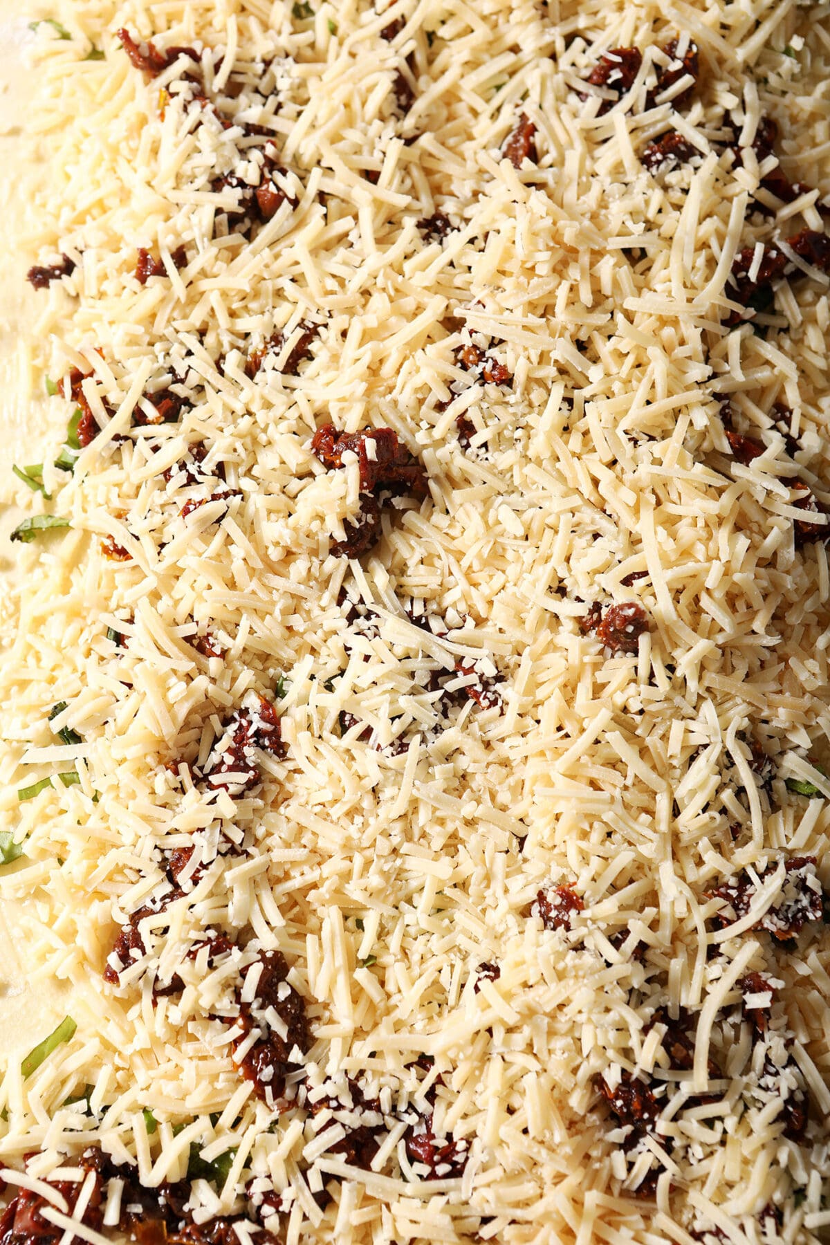 Shredded parmesan cheese on top of sun-dried tomatoes to make a puff pastry pinwheel