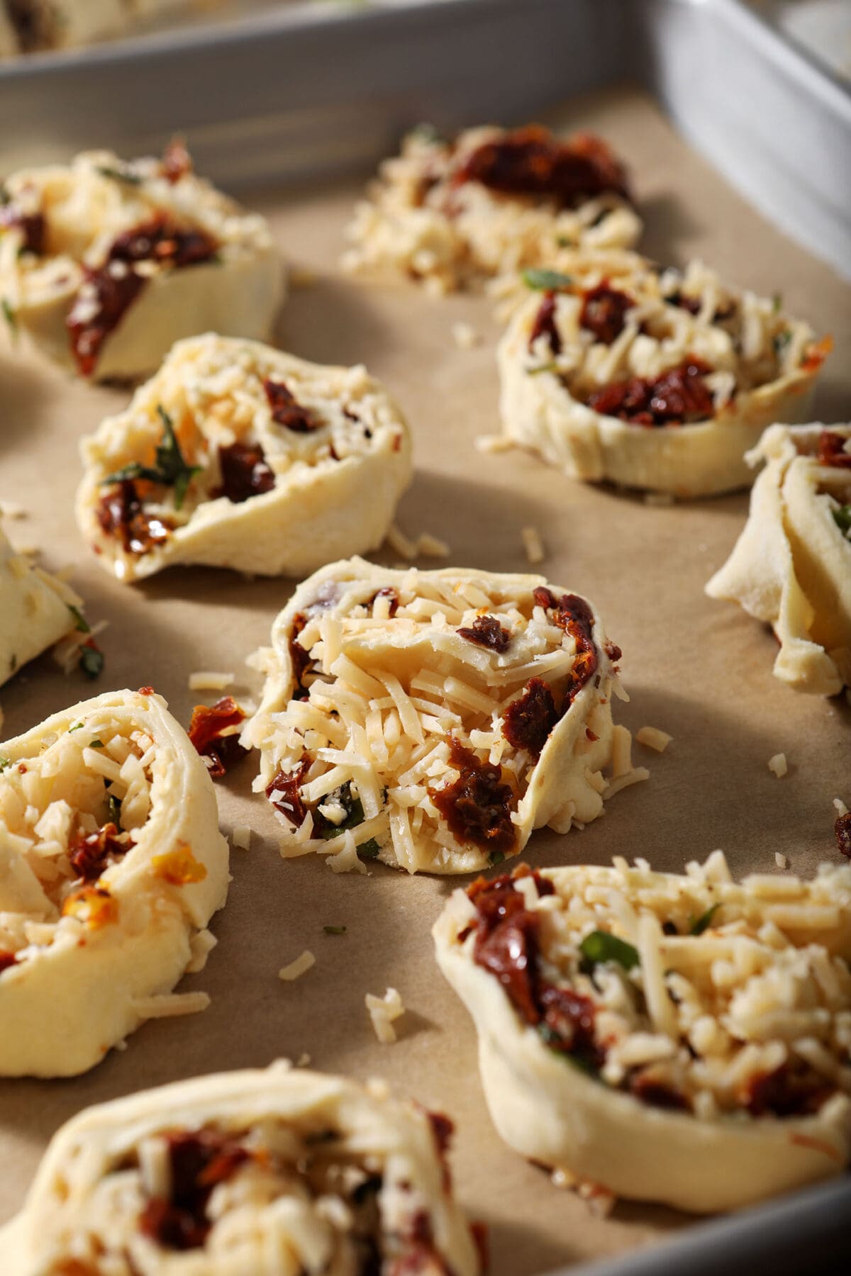 Sliced bruschetta pinwheels on a sheet pan before baking