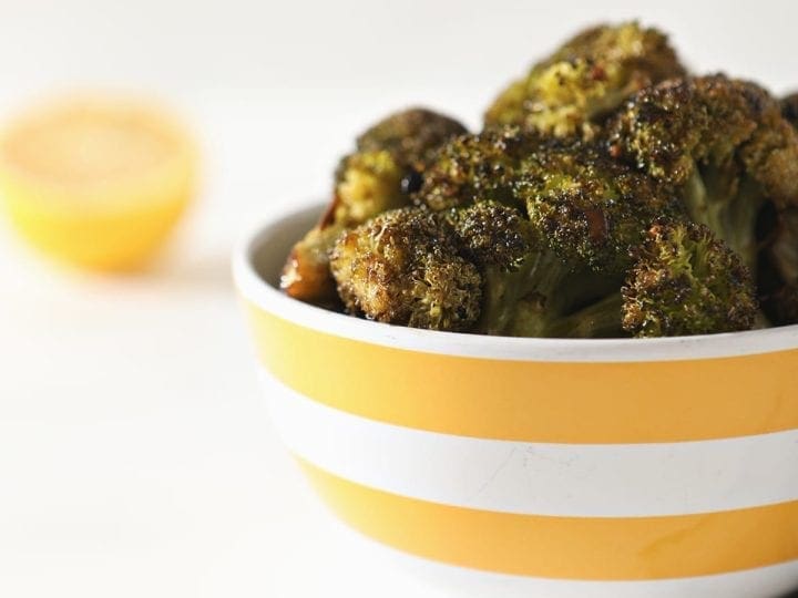 Roasted Broccoli with Lemon and Garlic in a yellow and white striped bowl sitting on a marble counter