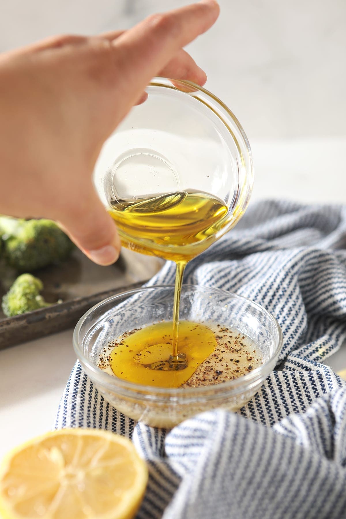 Oil pours into a lemon juice mixture in a clear glass bowl