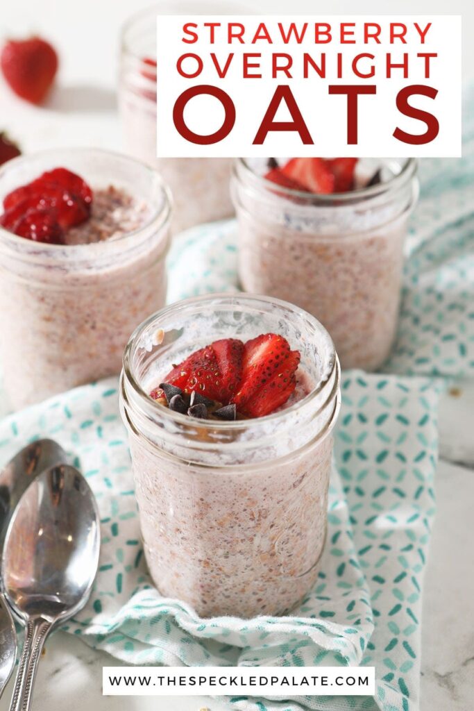 Four mason jars of overnight oats sit on a turquoise kitchen towel, garnished with strawberries and other ingredients with the text 'strawberry overnight oats'