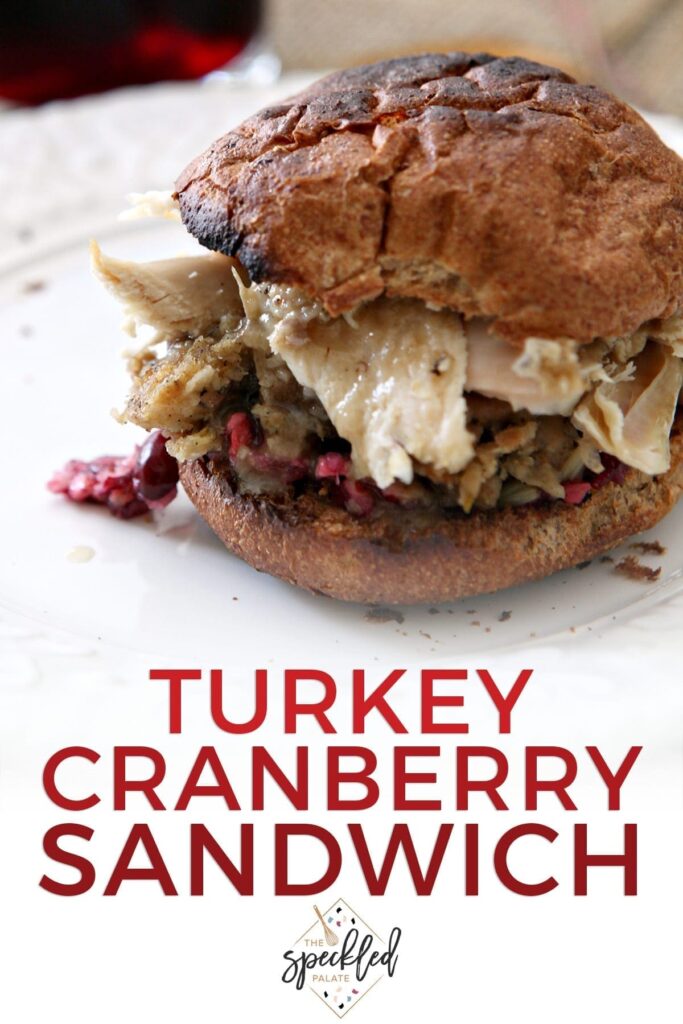 A toasted sandwich on a white plate with the text 'turkey cranberry sandwich'