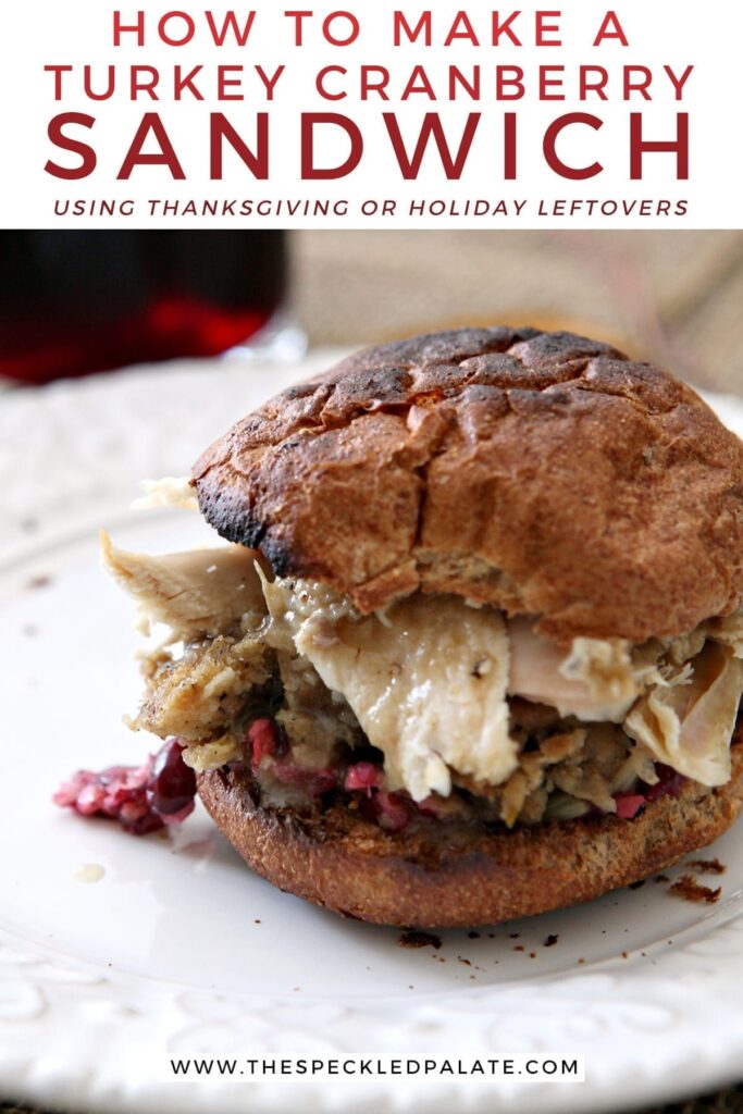 Close up of a sandwich with cranberry, turkey, stuffing and more on a white plate with the text 'how to make a turkey cranberry sandwich using thanksgiving or holiday leftovers'