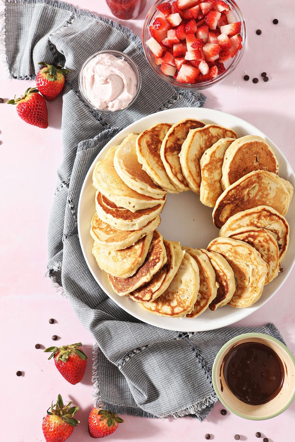 Old Fashioned Pancakes in a ring on a plate next to strawberries and a chocolate sauce