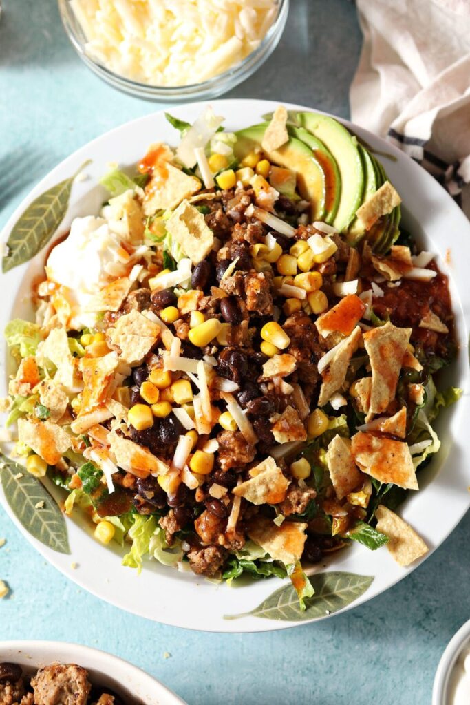 Close up of a bowl of Turkey Taco Salad topped with crushed tortilla chips, cheese and more