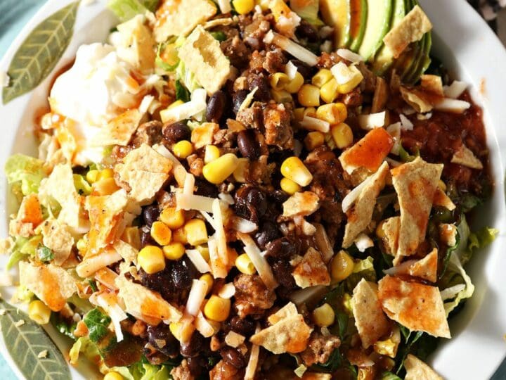 Close up of a bowl of Turkey Taco Salad topped with crushed tortilla chips, cheese and more