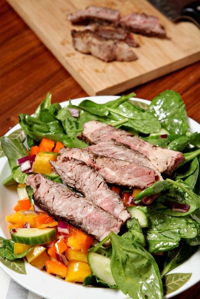 A plate of food on a table, with Salad and Steak