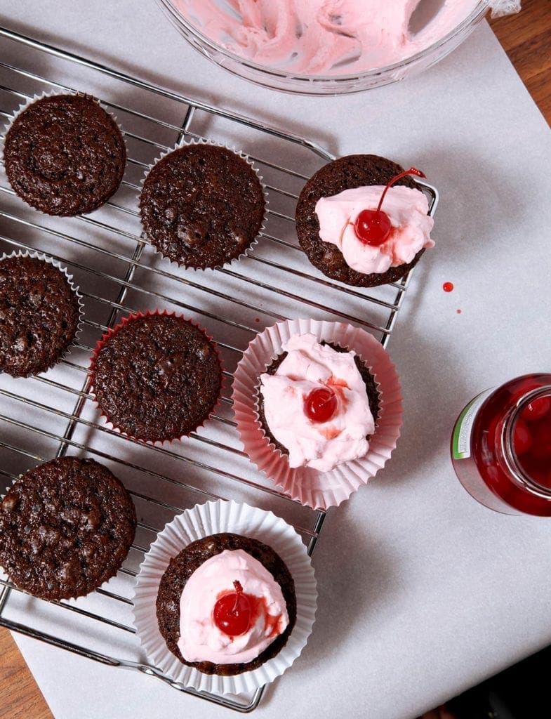 overhead of chocolate cupcakes with pink frosting and cherries 