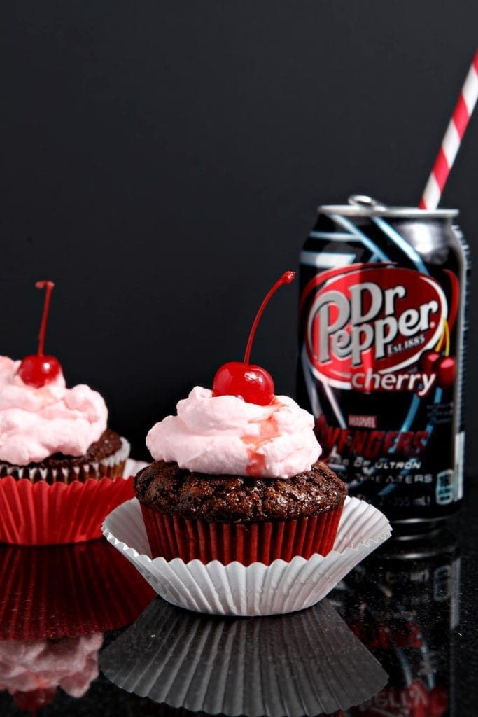 Two cupcakes in front of can of soda 