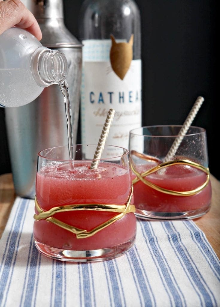 pouring sparkling water into a cocktail glass