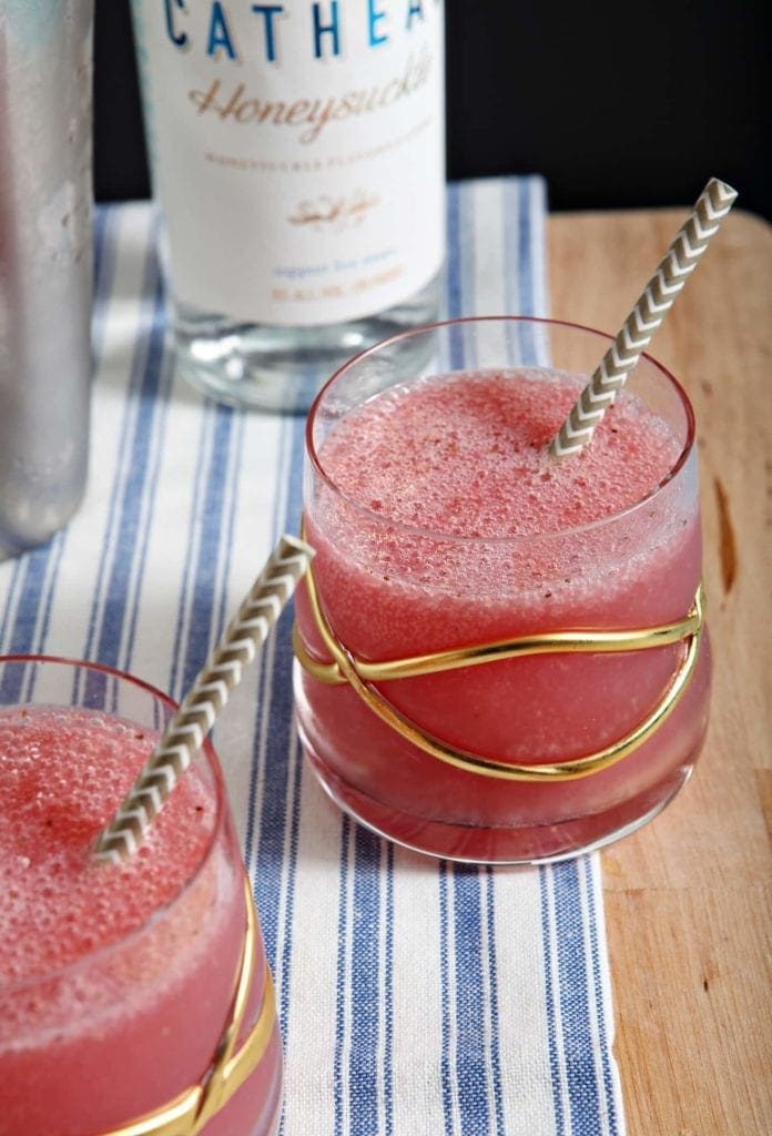 A close up of a glass cup on a table, with Strawberry and Vodka